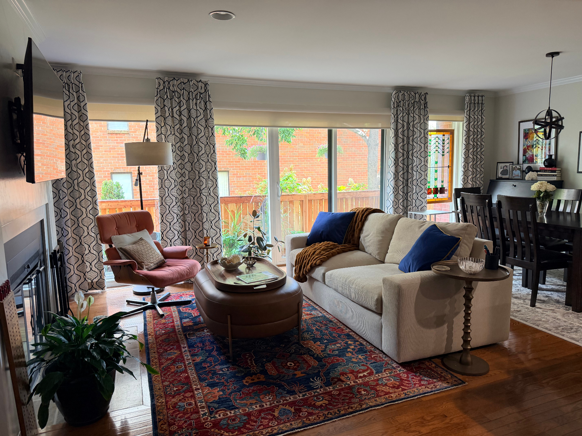 Bright living room with a cream sofa, coral accent chair, patterned rug, and sliding glass doors to a patio
